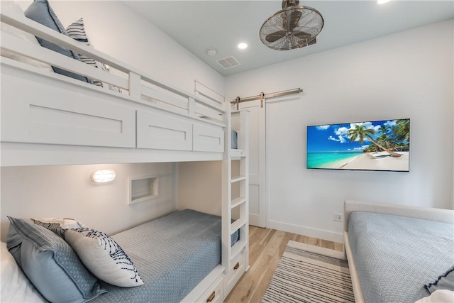 bedroom featuring a barn door and light hardwood / wood-style floors