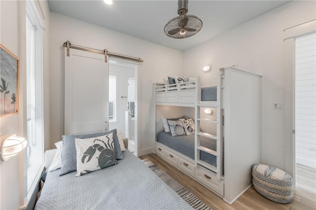 bedroom featuring multiple windows, light hardwood / wood-style flooring, and a barn door