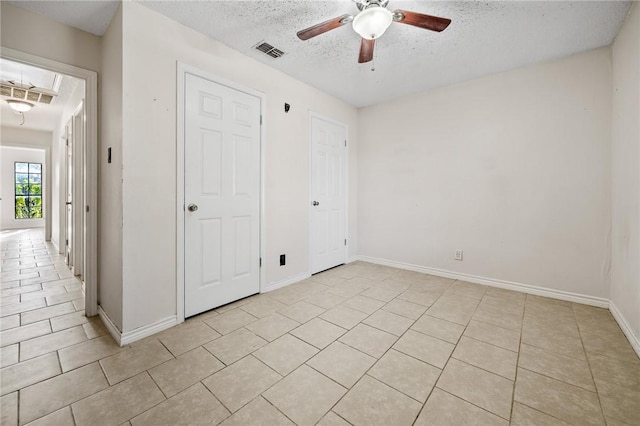 unfurnished bedroom with ceiling fan, light tile patterned floors, and a textured ceiling