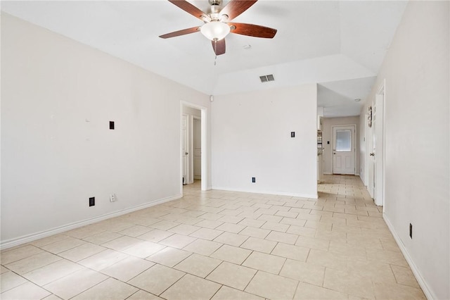 tiled empty room with a raised ceiling and ceiling fan