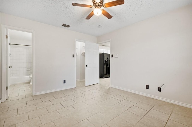 unfurnished bedroom featuring a walk in closet, ceiling fan, connected bathroom, light tile patterned flooring, and black fridge with ice dispenser