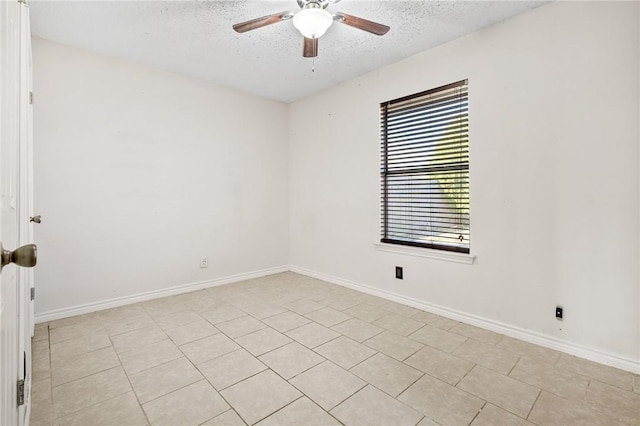 empty room featuring ceiling fan, light tile patterned floors, and a textured ceiling