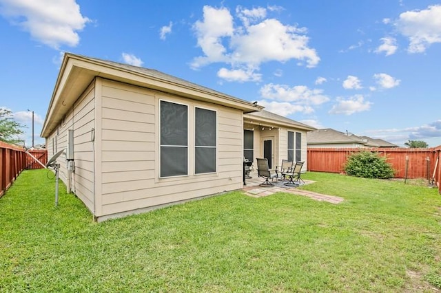 back of house with a fenced backyard, a yard, and a patio area