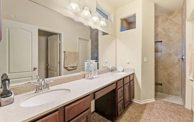 bathroom with tiled shower, tile patterned flooring, double vanity, and a sink