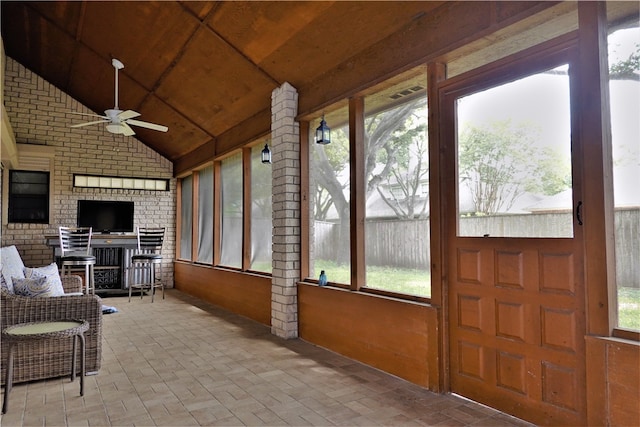 sunroom with lofted ceiling, a healthy amount of sunlight, ceiling fan, and wooden ceiling