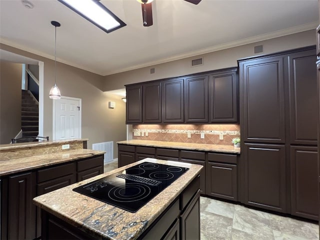 kitchen with tasteful backsplash, ornamental molding, black electric stovetop, hanging light fixtures, and a center island