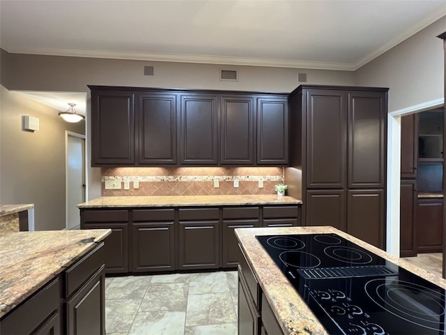 kitchen with decorative backsplash, black electric cooktop, dark brown cabinetry, and crown molding