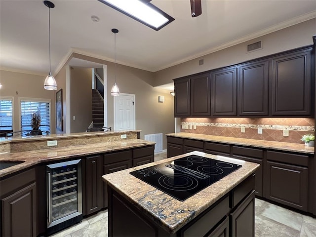 kitchen featuring black electric cooktop, a center island, beverage cooler, ornamental molding, and decorative light fixtures