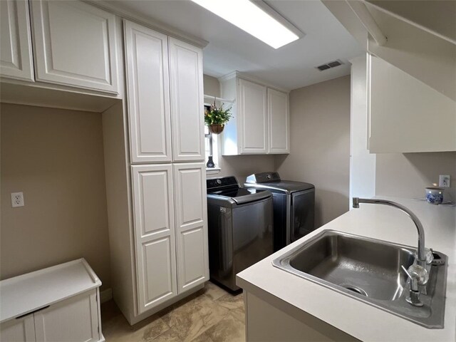 clothes washing area featuring cabinets, sink, and independent washer and dryer