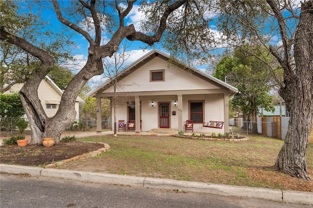 bungalow-style home featuring a porch, fence, and a front yard