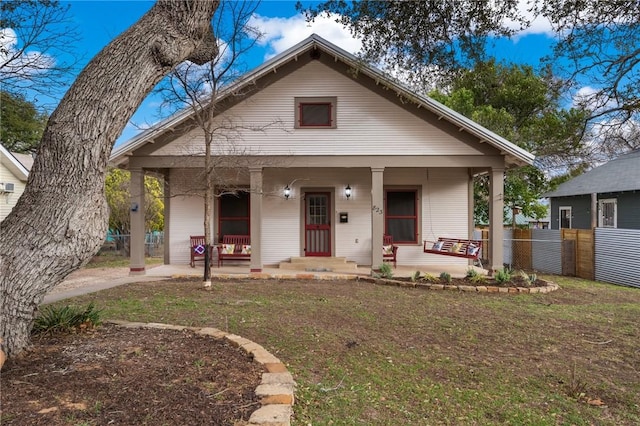 bungalow featuring a front yard, fence, and covered porch