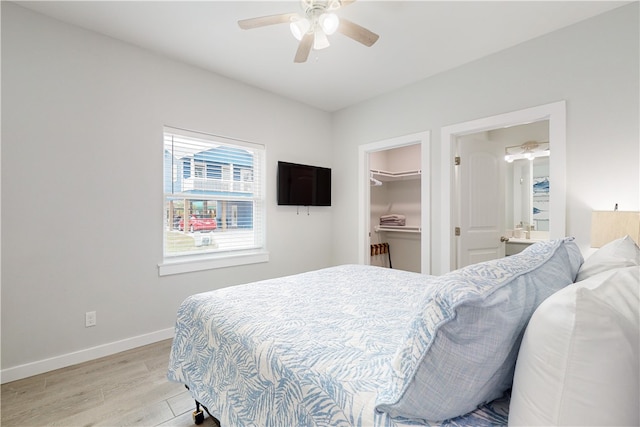 bedroom with light hardwood / wood-style floors, ceiling fan, a closet, and a walk in closet