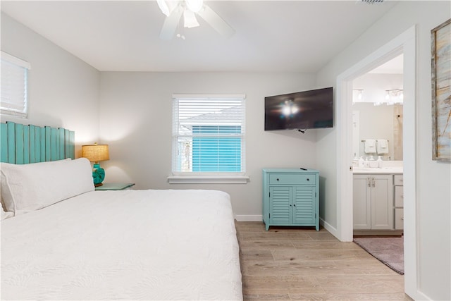 bedroom featuring light hardwood / wood-style floors, ceiling fan, and ensuite bath