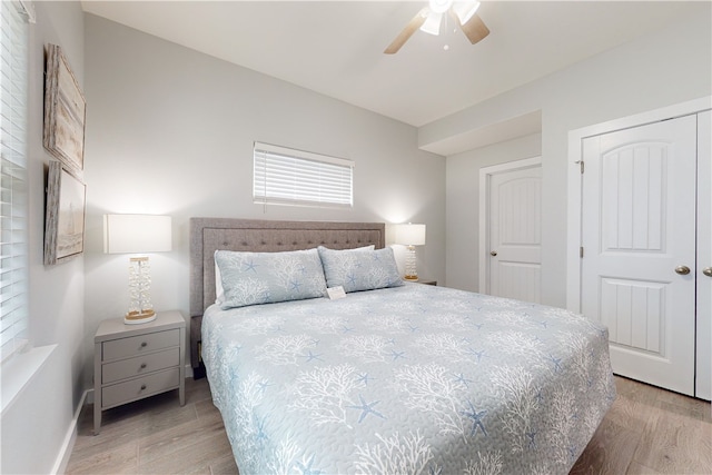 bedroom with light wood-type flooring, ceiling fan, and a closet