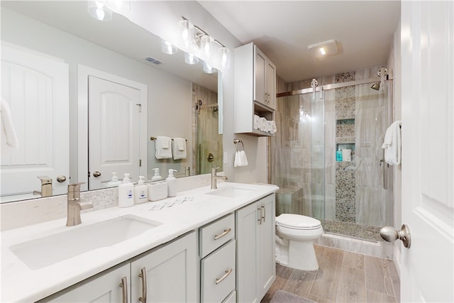 bathroom with hardwood / wood-style flooring, vanity, toilet, and an enclosed shower