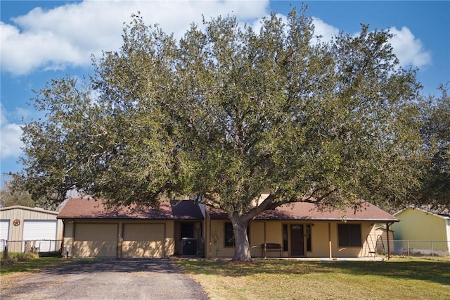 view of front of property featuring aphalt driveway, a front yard, fence, and an attached garage