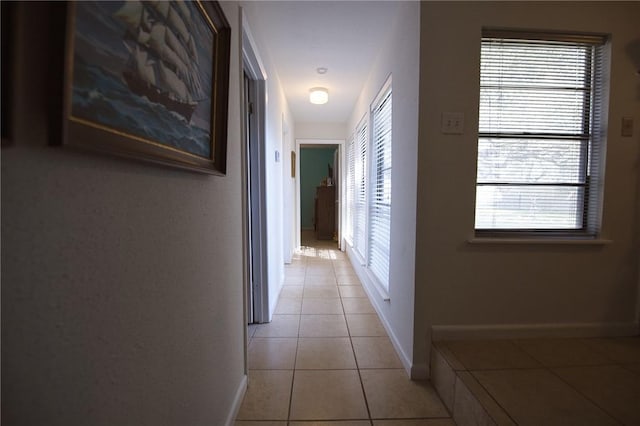 hall featuring plenty of natural light, light tile patterned flooring, and baseboards