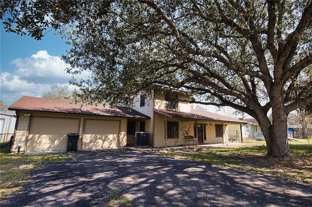 view of front of property with an attached garage, central AC unit, and aphalt driveway