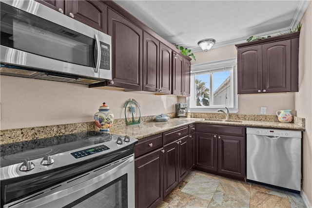 kitchen with dark brown cabinetry, appliances with stainless steel finishes, sink, and light stone counters