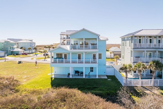 back of house featuring a balcony, a patio, and a yard