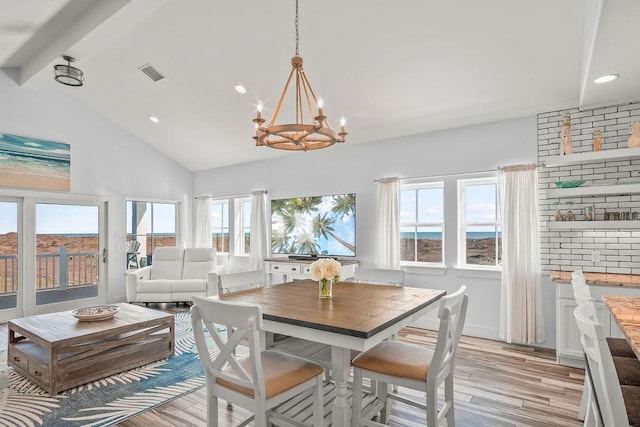 dining room with high vaulted ceiling, an inviting chandelier, light wood-type flooring, and beamed ceiling