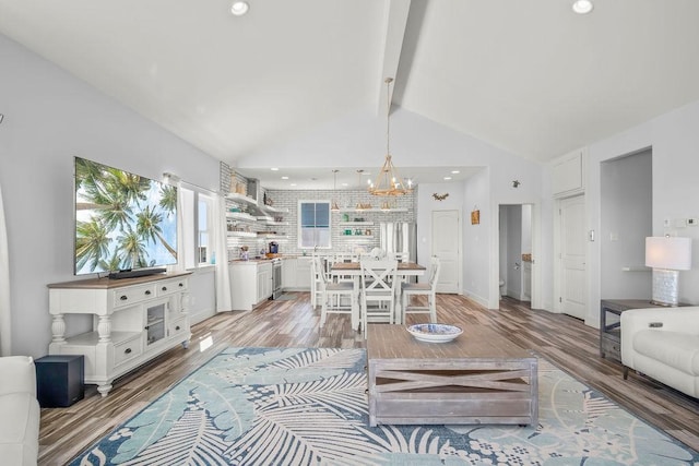 living room featuring light hardwood / wood-style flooring, an inviting chandelier, and vaulted ceiling with beams