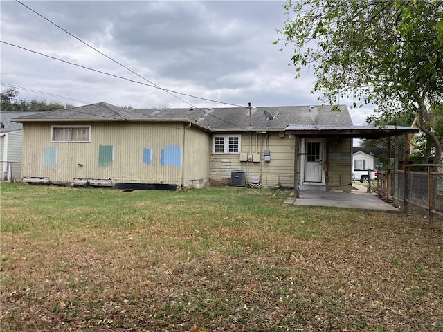 rear view of property featuring central air condition unit, a lawn, and a patio