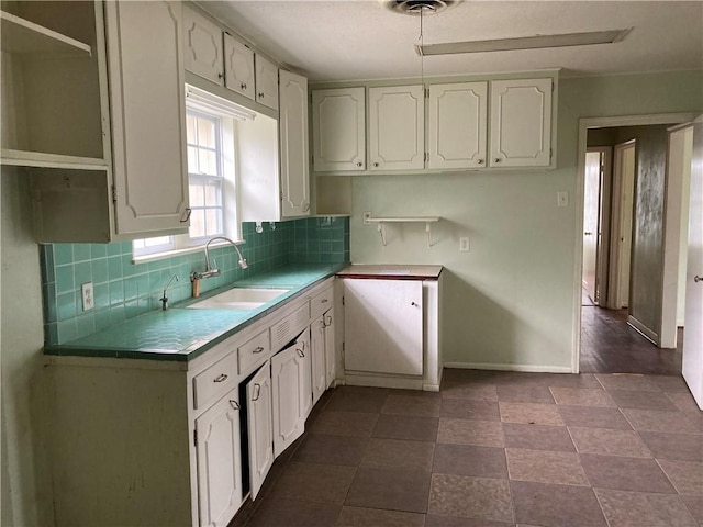 kitchen with tasteful backsplash, tile patterned flooring, sink, and white cabinetry