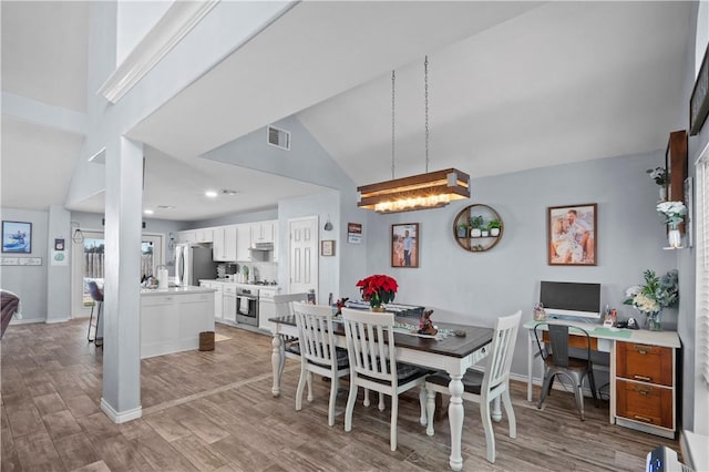 dining area with light hardwood / wood-style floors, lofted ceiling, and a notable chandelier