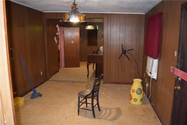 interior space with wooden walls, a textured ceiling, an AC wall unit, and crown molding