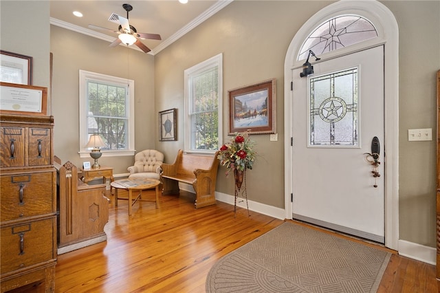 entrance foyer with light hardwood / wood-style floors, a wealth of natural light, and crown molding