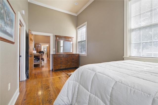 bedroom with wood-type flooring, multiple windows, and crown molding