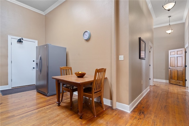 dining space featuring light wood-type flooring, crown molding, and a towering ceiling