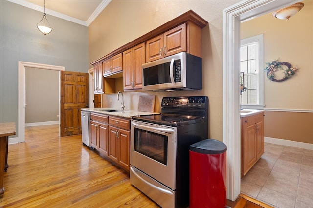 kitchen featuring sink, light wood-type flooring, ornamental molding, decorative light fixtures, and stainless steel appliances