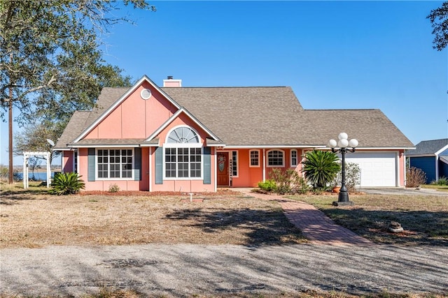 view of front facade with a garage, roof with shingles, driveway, and a chimney