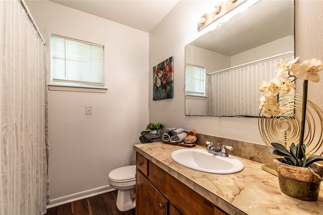 bathroom with hardwood / wood-style floors, a wealth of natural light, vanity, and toilet