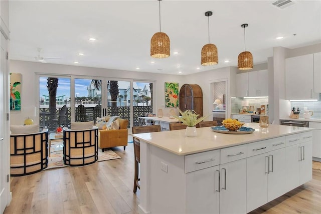 kitchen featuring white cabinetry, a kitchen island, pendant lighting, and light hardwood / wood-style floors