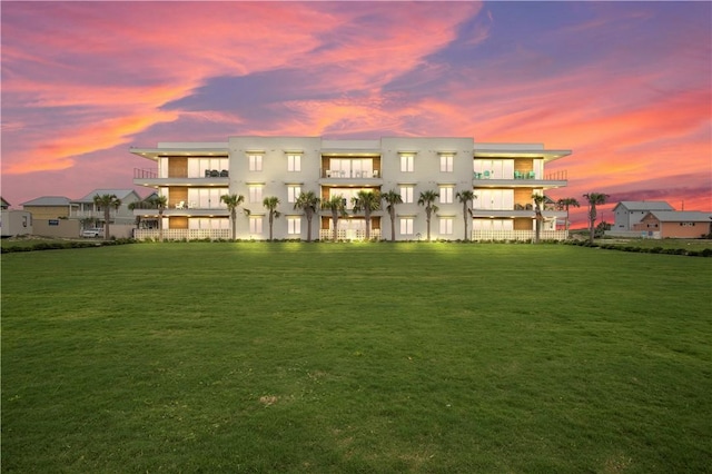 back house at dusk featuring a lawn