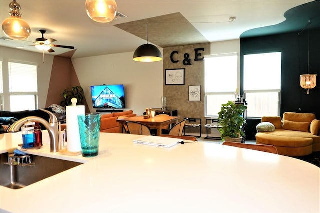 interior space featuring ceiling fan, sink, and hanging light fixtures