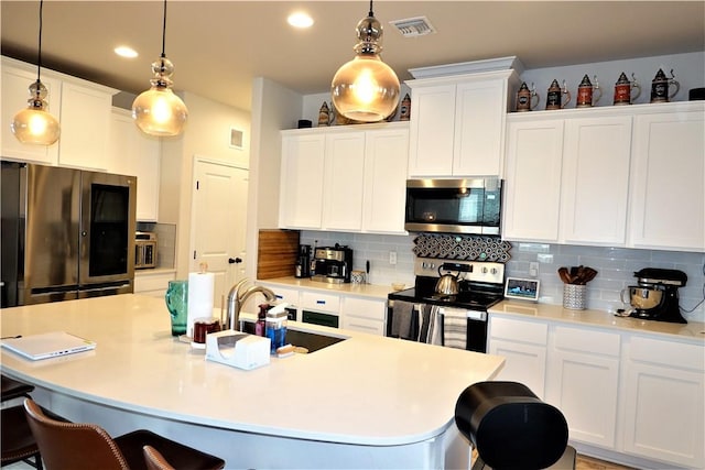 kitchen with stainless steel appliances, pendant lighting, white cabinets, and a kitchen bar