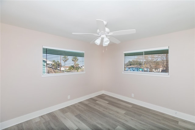 spare room with a wealth of natural light, wood-type flooring, and ceiling fan