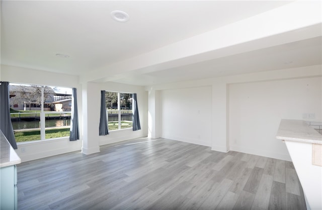 unfurnished living room featuring light hardwood / wood-style floors and a water view