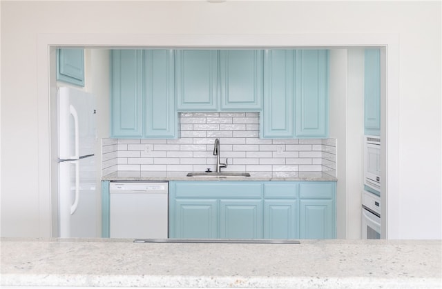 kitchen with blue cabinets, white appliances, sink, and backsplash