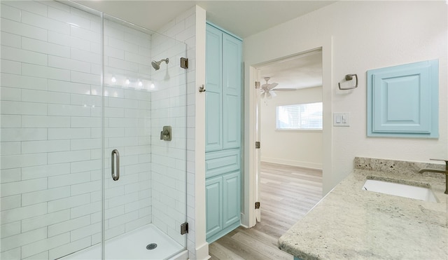 bathroom featuring ceiling fan, wood-type flooring, vanity, and a shower with shower door