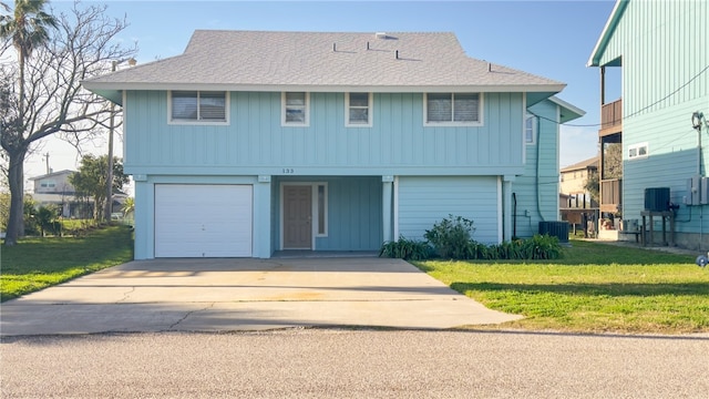 front facade featuring a garage, cooling unit, and a front lawn