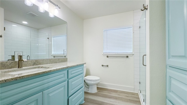 bathroom featuring wood-type flooring, vanity, toilet, and an enclosed shower