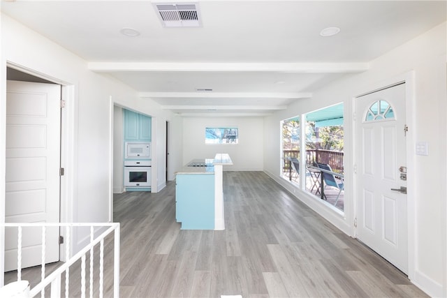 interior space with light wood-type flooring and beam ceiling