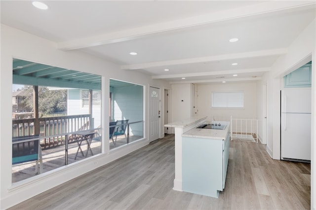 kitchen with white refrigerator, beam ceiling, light stone countertops, light hardwood / wood-style floors, and black electric cooktop