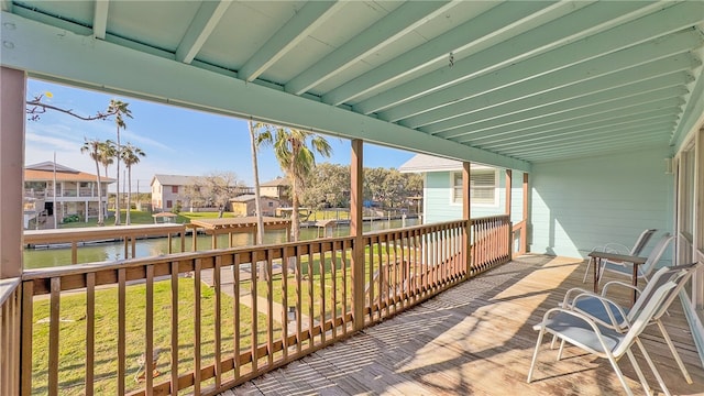 sunroom / solarium with beamed ceiling, plenty of natural light, and a water view