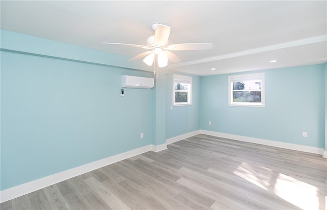 unfurnished room with ceiling fan, light wood-type flooring, and a wall mounted air conditioner